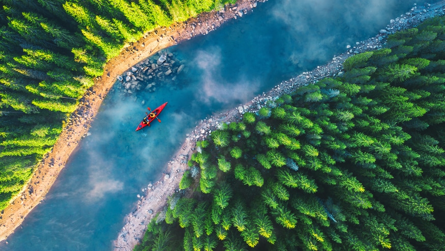Aerial view of rafting boat or canoe in mountain river and forest