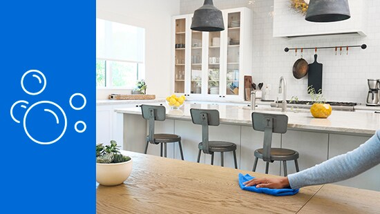 Person wiping a kitchen counter with a blue cloth
