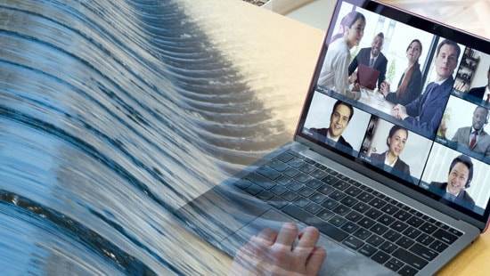  Laptop computer on desk with virtual meeting happening on screen with semi-transparent image of water flowing over.
