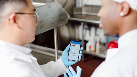 Foodservice Intelligence Powered by Ecolab with two kitchen staff looking at a cell phone.