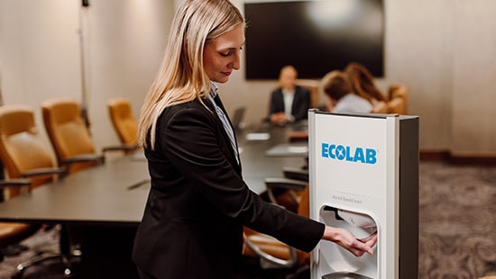 Woman using an Ecolab Nexa hand sanitizing station