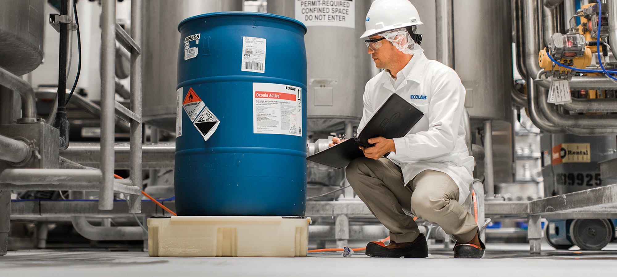 Ecolab technician at a plant looking at a barrel of product