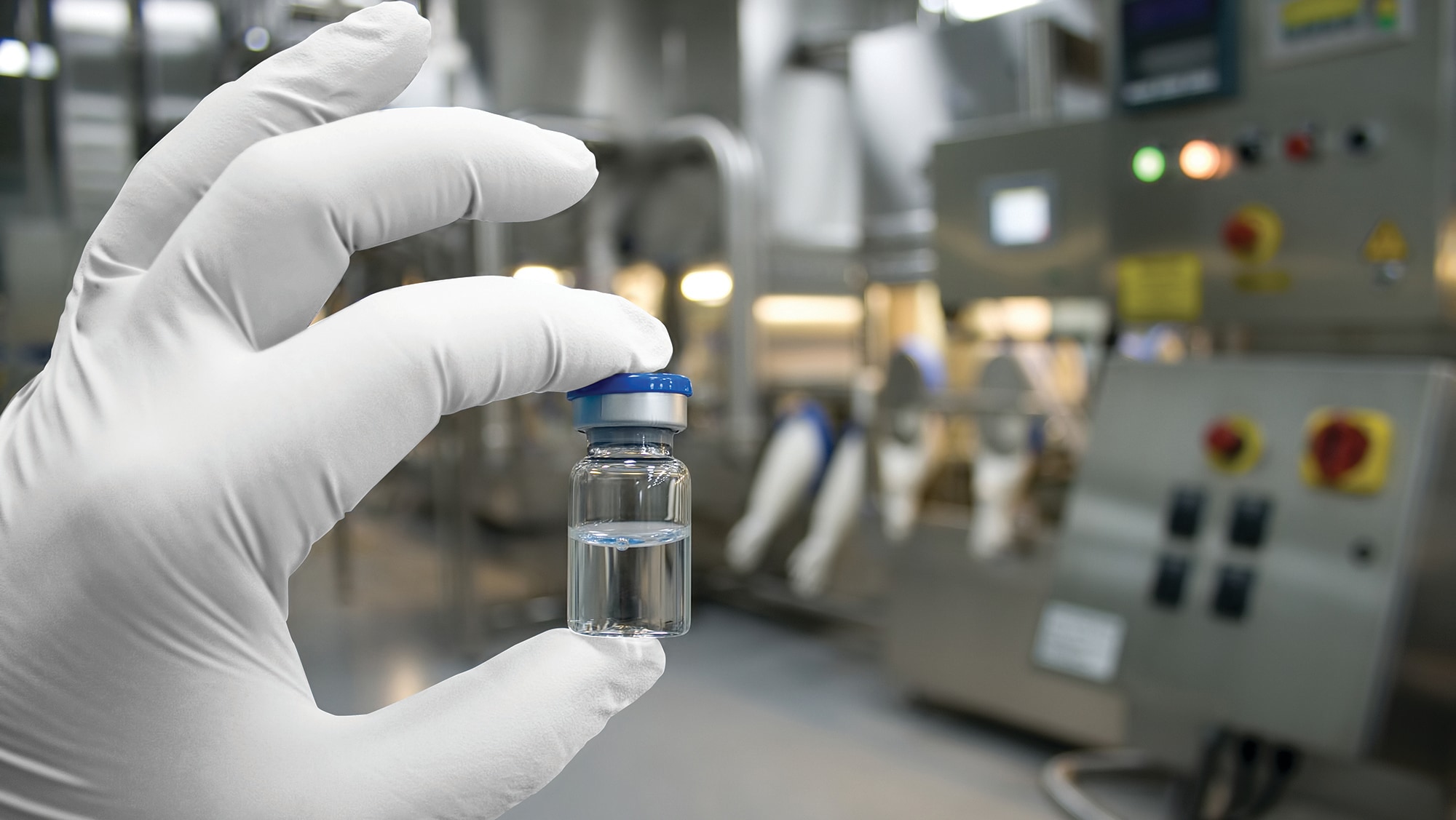 Gloved hand holding a small vial