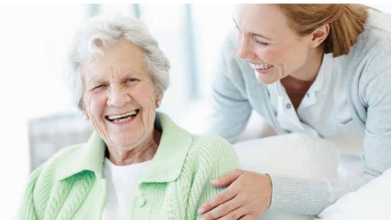 An image of a long term care assistant helping out an elderly woman.