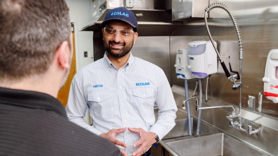Pest expert in restaurant back of house discussing pest risk with manager.