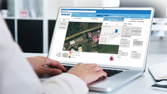 An Ecolab expert is analyzing pest data and insight on a laptop. 
