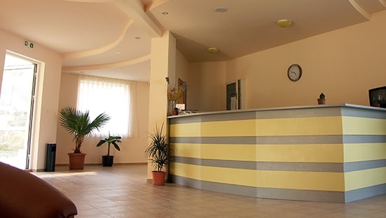 Hospital lobby with tile floors and a yellow striped reception desk 