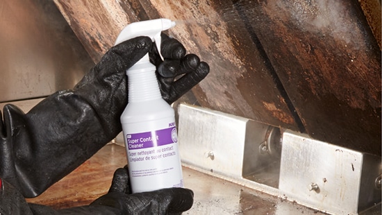 Gloved hands spraying contact super cleaner and surface sanitizers onto a greasy air vent.
