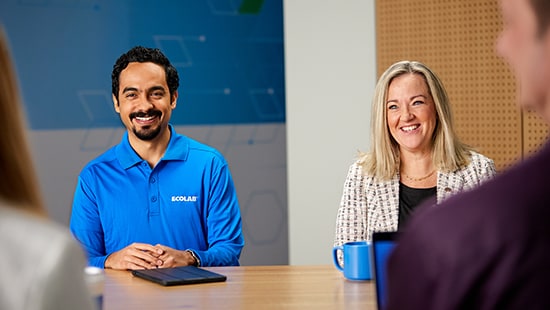 Ecolab employees smiling at two other people across a table