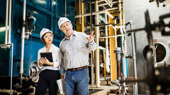 Two associates with hard hats walking through a manufacturing facility 