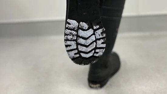 Person showing bottom of boot with Ecolab Boost Tread Defense™ QF product on the tread.