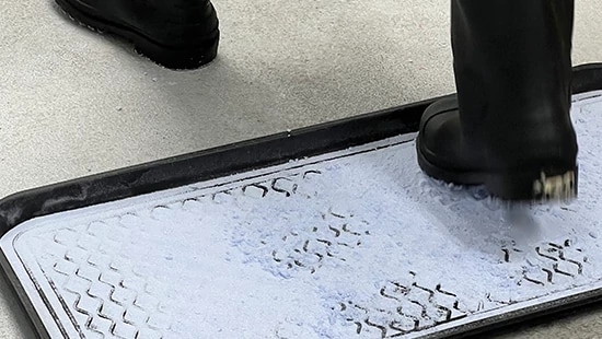 Person stepping on mat filled with Ecolab Boost Tread Defense QF.