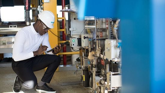 Man in hard hat checking equipment in manufacturing site 