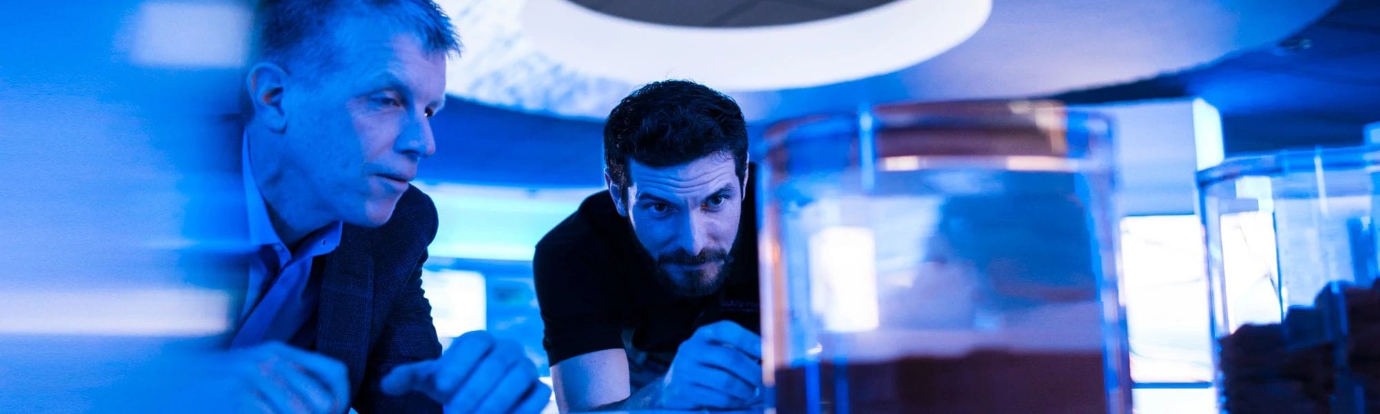 Two associates examining the contents of glass containers.