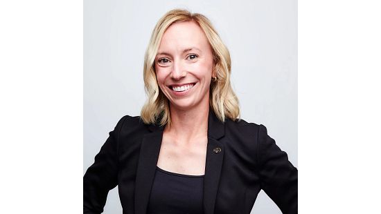 Person with blonde hair in a black blazer and top, face blurred.