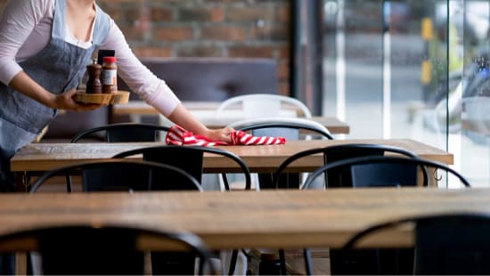 restaurant server wiping table in front of house
