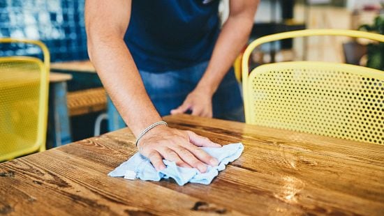 Foodservice worker wiping down a table.