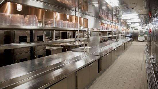 Front of House waitstaff standing in restaurant entranceway holding a tablet and smiling.