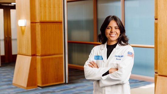 Professional in a white lab coat with an Ecolab logo, standing with arms crossed in a modern indoor hallway.