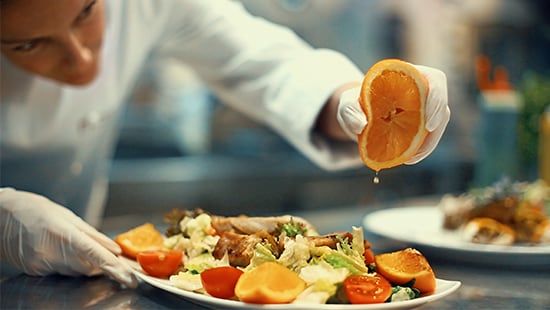 Chef preparing meal in clean kitchen wearing food safety gloves