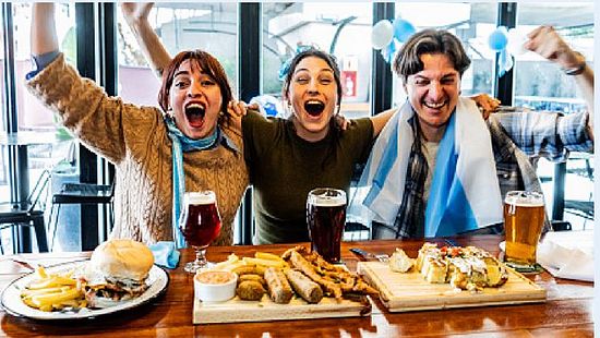 A group of people sitting at a restaurant table with raised arms