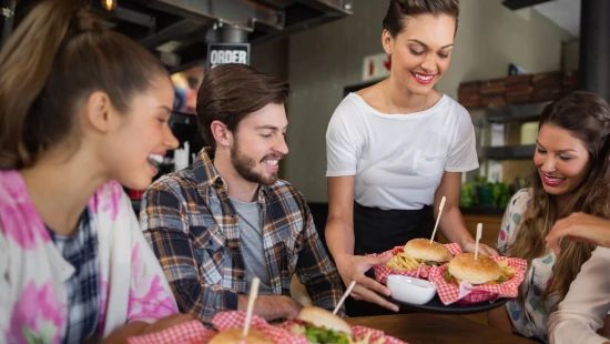 A group of people sitting at a restaurant table with raised arms