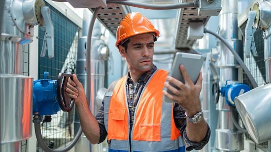Engineer looks at tablet and adjusts cooling tower