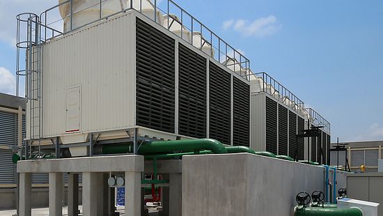 Two operators standing outside a large cooling tower.