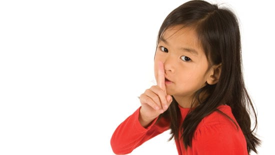 Young girl making shushing sign.