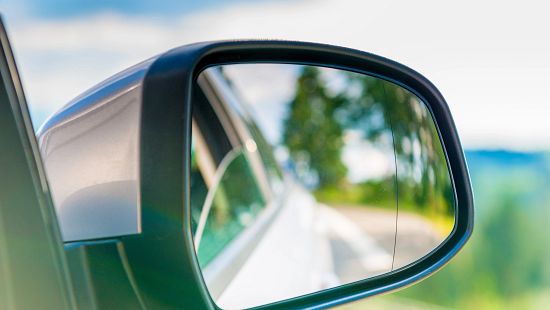 car side mirror with a reflection of the beautiful scenery in it, close-up