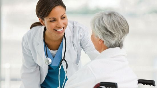 Health care provider caring for elderly person in wheelchair